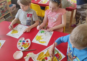 Dzieci malują wielkanocne obrazki.